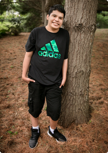 Jose, who waits to be adopted, smiles as he leans against a tree.