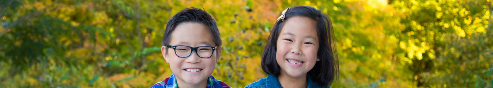 School-age Korean boy and girl siblings smile outside