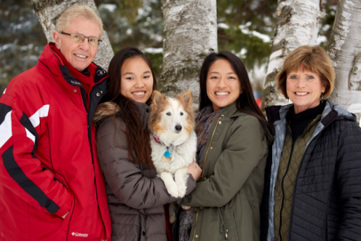 Family with white parents and Asian adopted daughters and dog