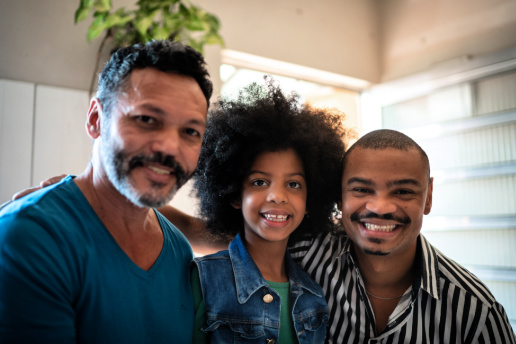 Two dads pose with foster or adoptive daughter
