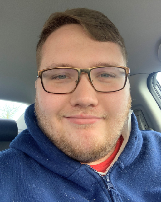 Selfie of adult male with brown hair wearing glasses and blue hoodie