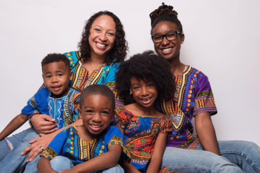 Two moms and their three children pose for family picture in matching shirts