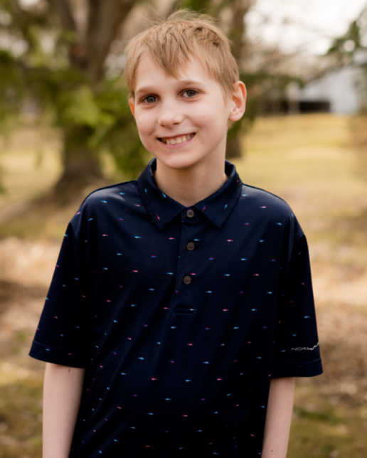 11 year old boy with blond hair smiles outside