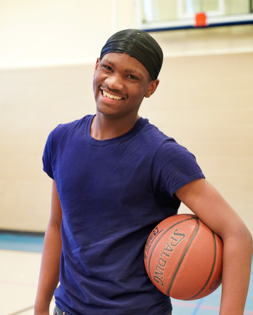 African American teen boy smiles with basketball