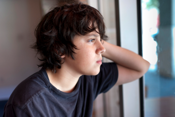 Pre-teen boy looks pensive out of window