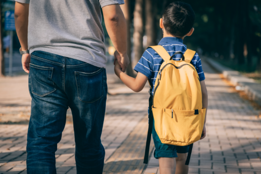 Father holds hand with child as they walk to school