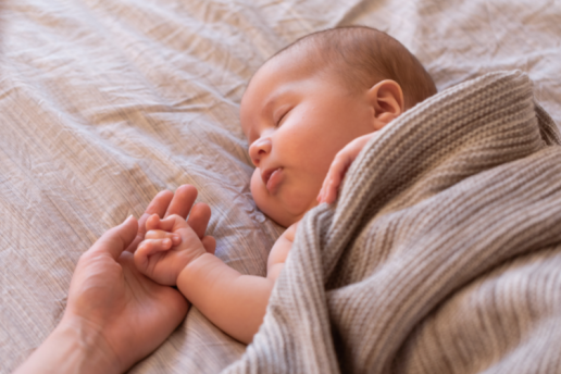 Sleeping newborn holds hand of parent