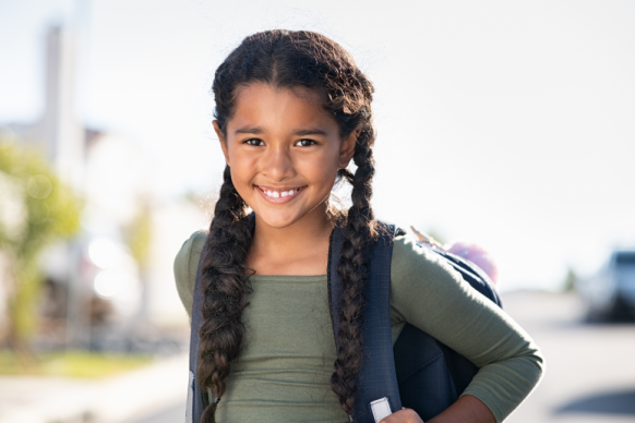 Happy young girl smiles with backpack
