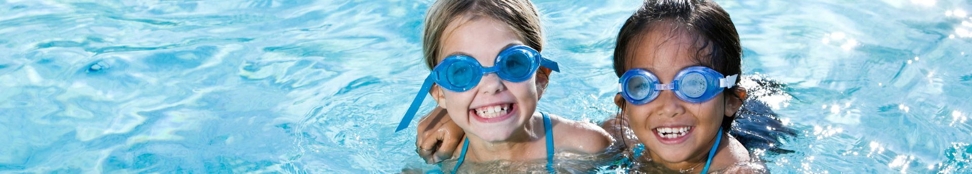 Two girls swimming together wearing goggles