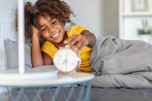 Young girl waking up with alarm clock