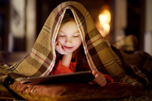 Little boy reading under a blanket