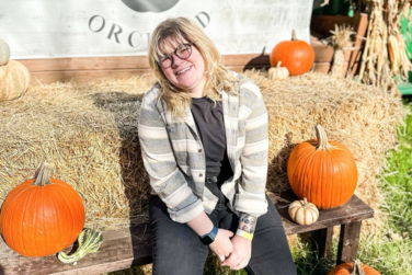 Portrait of adult female at pumpkin patch wearing flannel shirt and black jeans