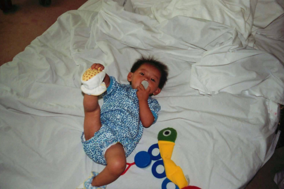 Baby with toys on bed