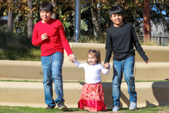 Two boys holding hands with young girl
