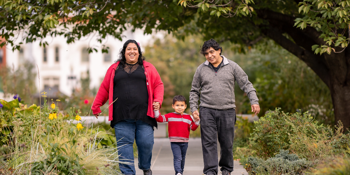 a couple walking with their child through a park or garden