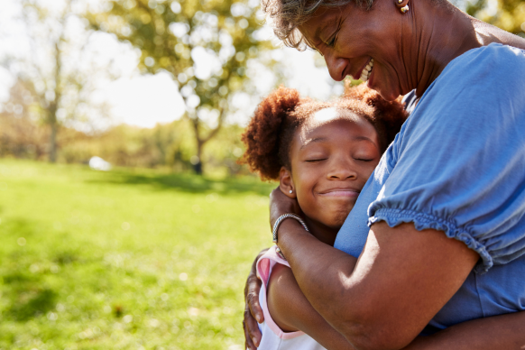 young girl and older woman hugging on a sunny day