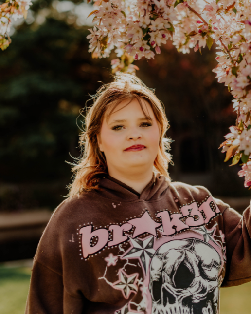 Makennah posing by a flowering tree on a sunny spring day