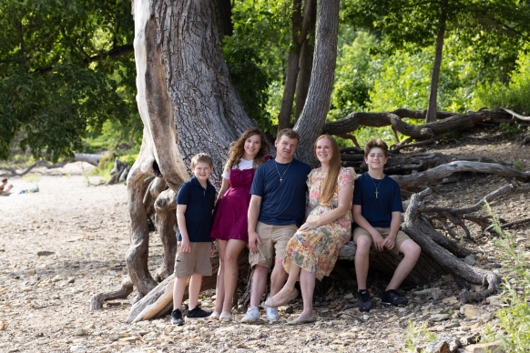 Weckman family posing by a large tree on the shore of a river