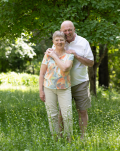 Harry and Martha Mueller standing in tall grass with green trees in the background