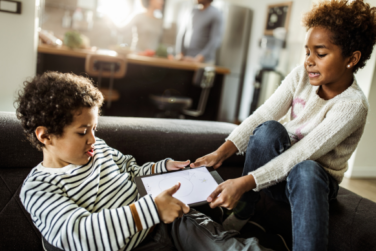 two young siblings fighting over a tablet