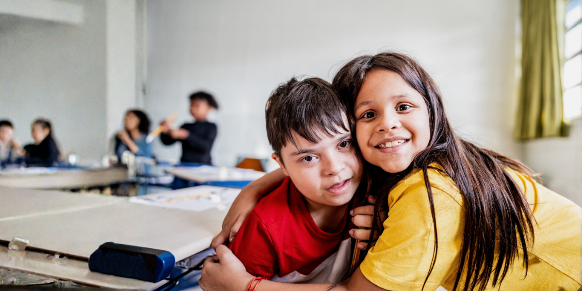 girl with a yellow shirt hugging a boy in a red shirt with Down's syndrome